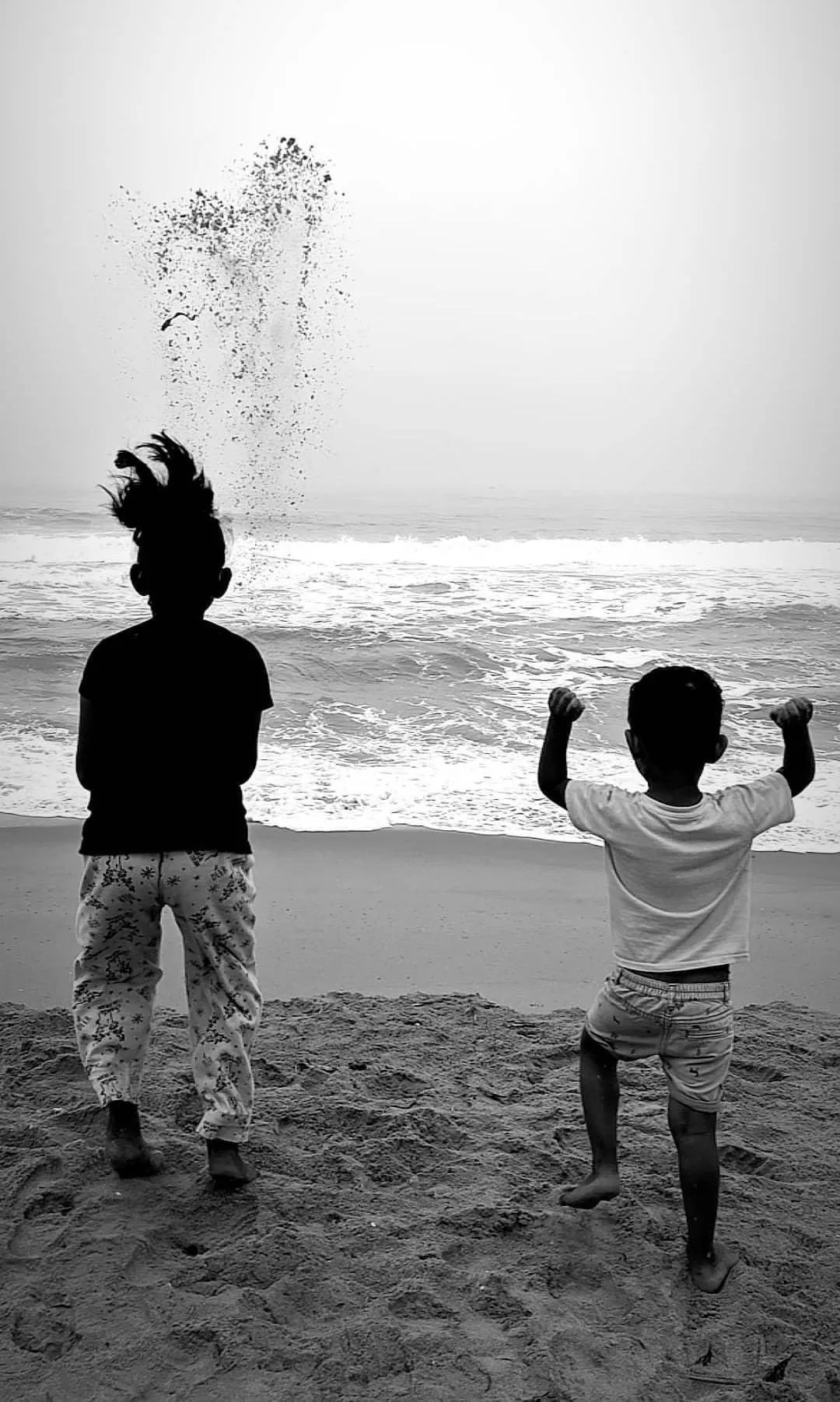 Two children playing at the edge of the sea.