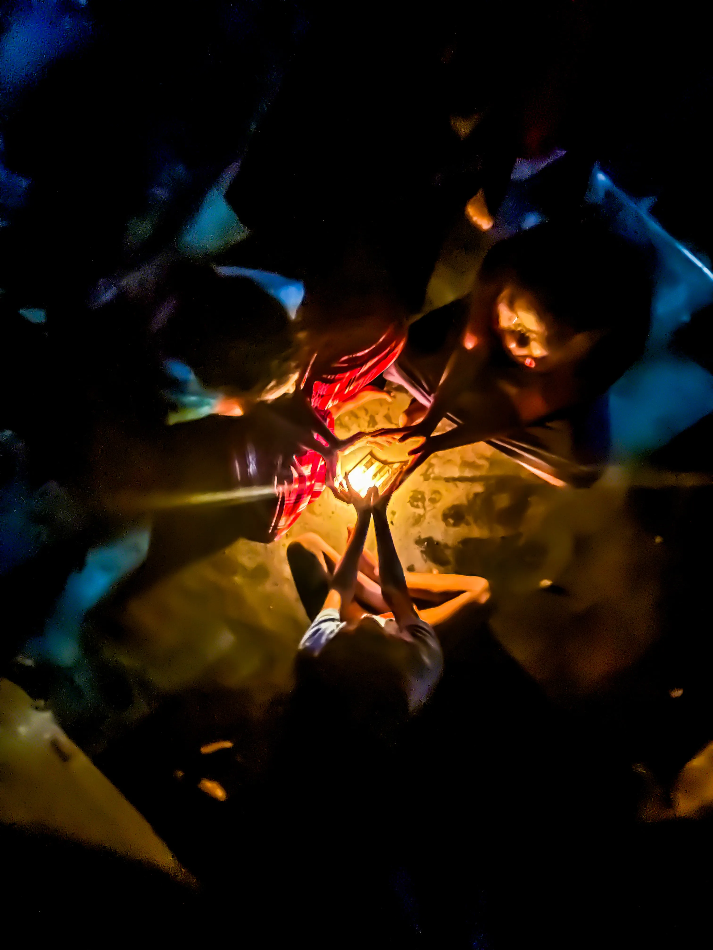Children gathered around a single glowing light in the dark.
