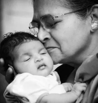 A grandmother holding a sleeping newborn close.