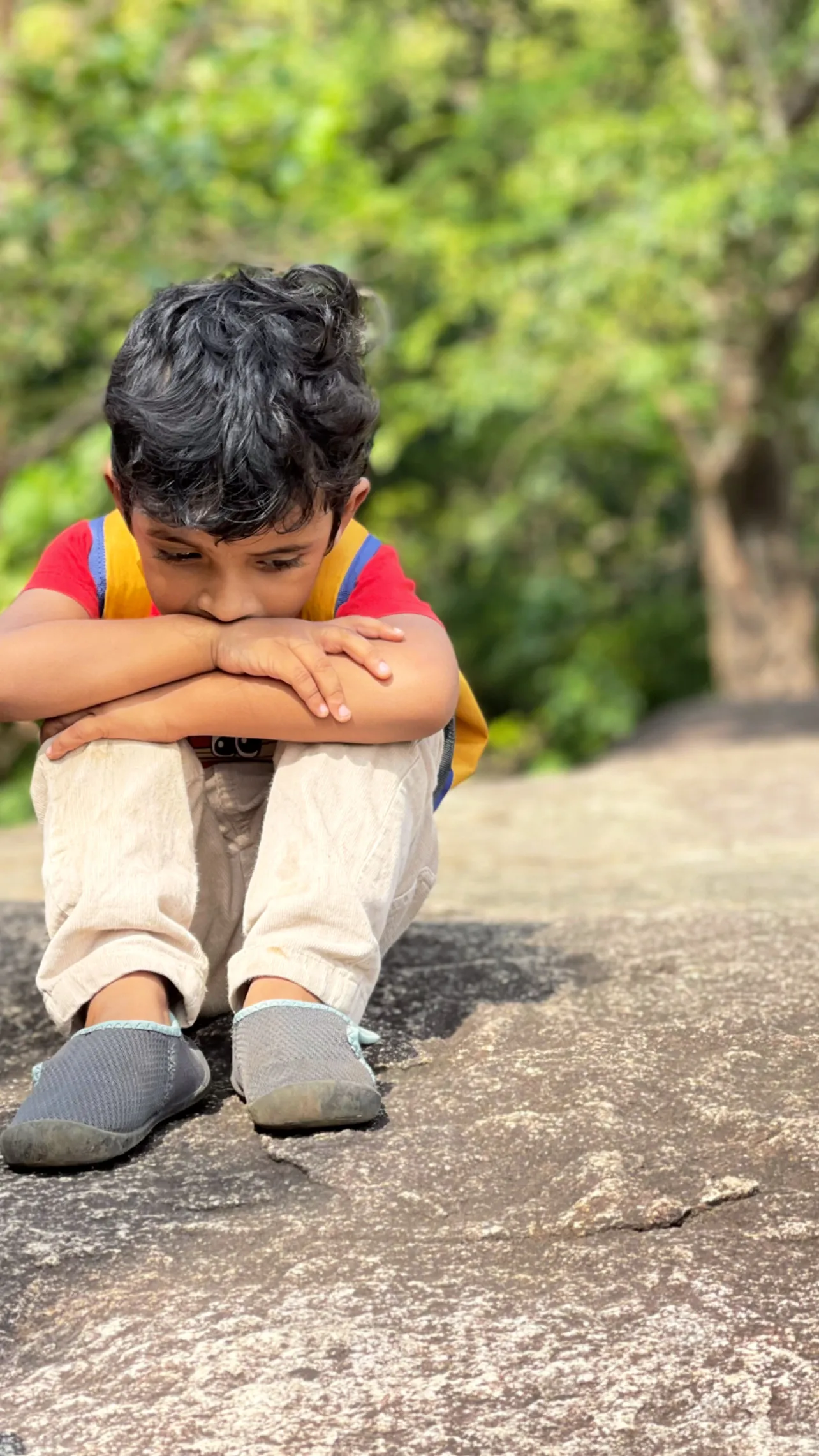 A child sitting on a rock, lost in thought.